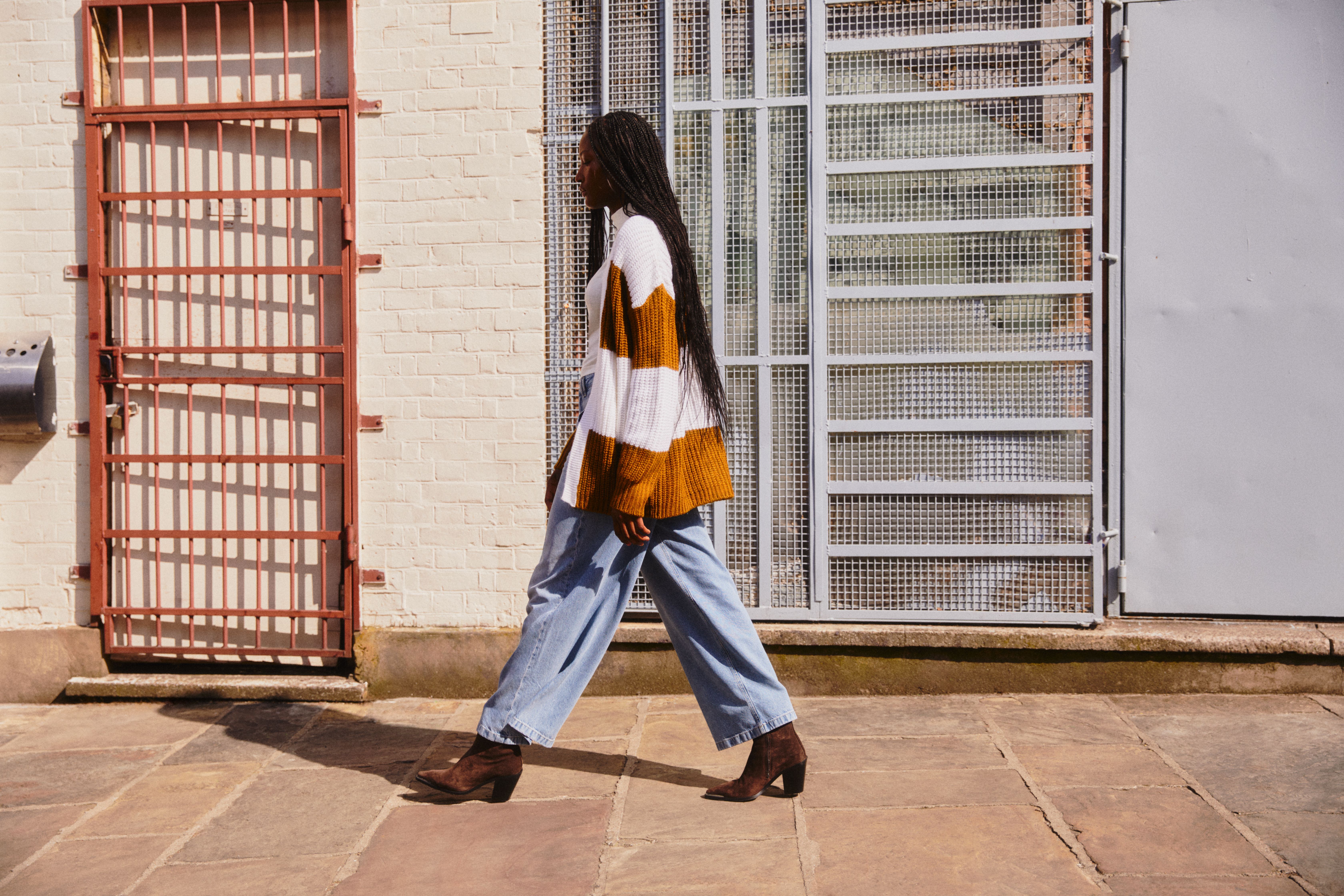 Woman walking by wearing stylish loose jeans and a knit jacket